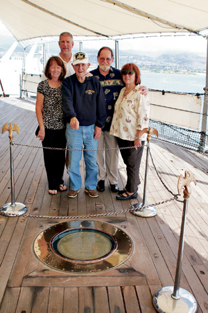 Skylar Fredrickson, with family members, points to the spot where the Japanese surrendered aboard the USS Missouri | USS Missouri Memorial Association photo