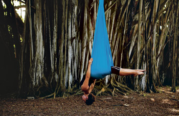 Lynch demonstrates an aerial yoga pose using a silk hammock