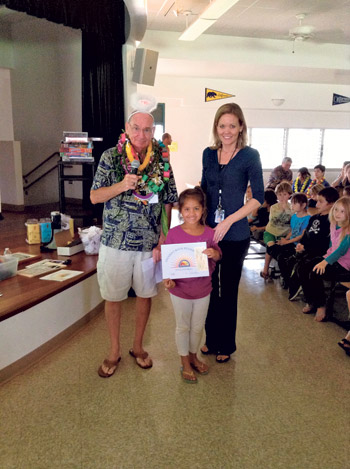 Cox presents a check and certificate to a winner of the Rotary Book Review Contest, Kilauea Elementary School second-grader Kalei Mersberg, with principal Sherry Gonsalves