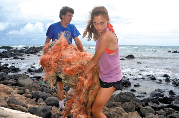 Volunteers hawl away a mass of fishing net at Anahola. Photo from Surfrider Foundation