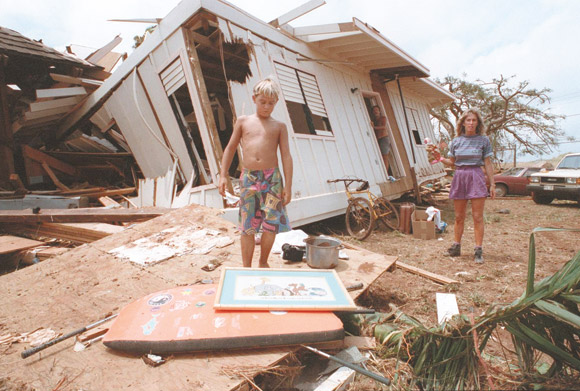 Ryan Trenton, 8, stands outside the remains of his house that had previously stood on Hoona Road near Poipu before being shoved a few hundred feet inland and into another house by shore surge created by Hurricane Iniki. Dean Sensui / Honolulu Star-Advertiser photo 