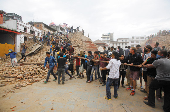 Volunteers help remove debris from a building that collapsed in Kathmandu after a 7.9 earthquake shook Nepal April 25 | AP photo