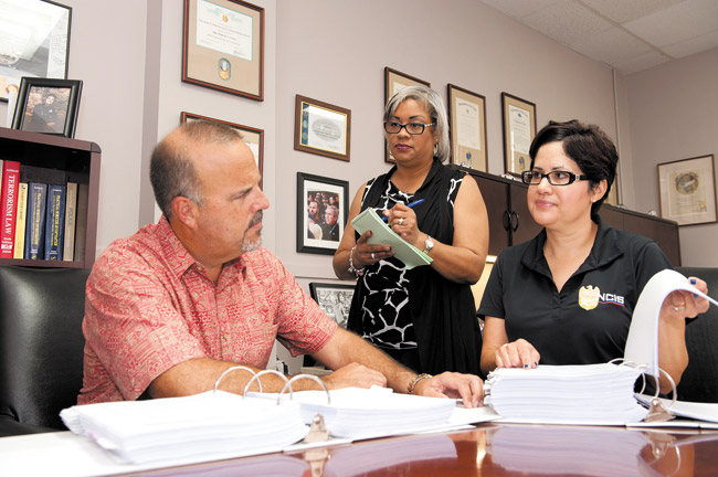Tony Cox, Special Agent in Charge, discusses a significant fraud investigation with Special Agent Jo Dempski (right) and Victoria Ferreira, program support assistant 