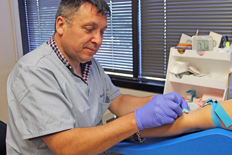 Andrew Preston, Malama Pono's prevention specialist and medical assistant, draws blood from a patient 