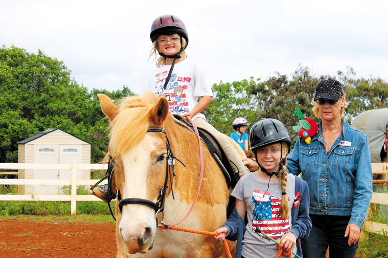 Elizabeth Wallace rides Ivan with Jazzy Hanft and volunteer Joanne Stradley by her side