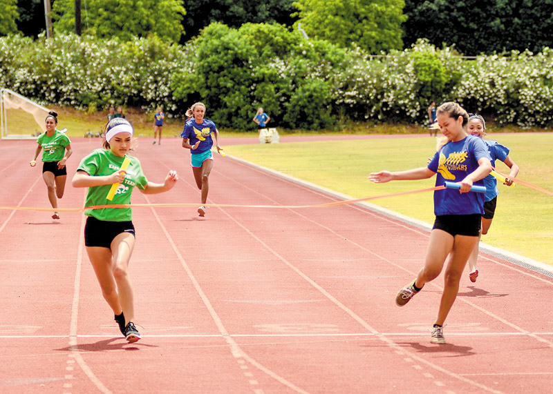 Island School's Jenna Takeuchi edges out Kapaa Middle's Talia Suzuki at the finish line in the 400-meter relay (grade 8) 