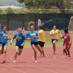 Chaos is averted as competitors successfully pass batons after the first leg of the girlsâ€™ sixth and seventh grade 440-yard relay.